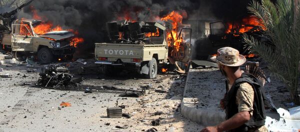 A fighter from the pro-government forces loyal to Libya's Government of National Unity (GNA) looks at GNA forces' vehicles burning - Sputnik Mundo