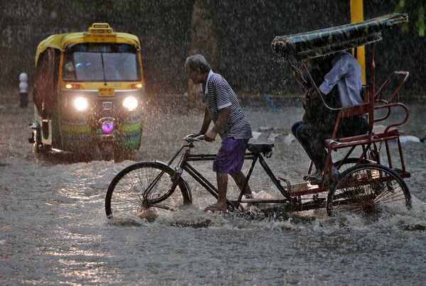 Un conductor de 'rickshaw' durante una fuerte lluvia en Nueva Delhi. - Sputnik Mundo