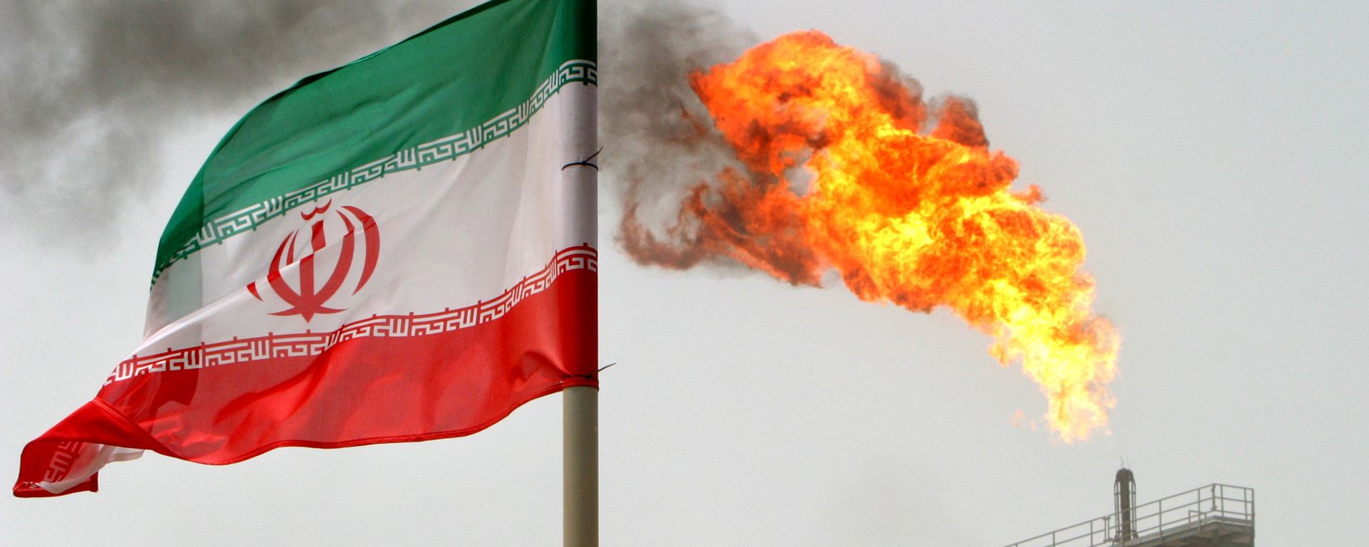 La bandera de Irán con una llama de gas en una plataforma de producción de petróleo al fondo La bandera de Irán con una llama de gas en una plataforma de producción de petróleo al fondo - Sputnik Mundo, 1920, 21.02.2022