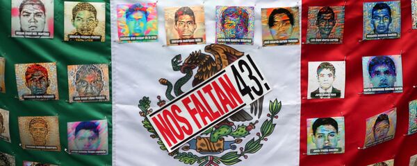 A Mexican flag and some pictures of the 43 missing students is seen in a march to demand justice for the 43 missing students of Ayotzinapa College Raul Isidro Burgos to mark the two-year anniversary of their disappearance in the state of Guerrero, in Mexico City, Mexico, September 26, 2016. - Sputnik Mundo