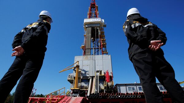 Workers look at a drilling rig at a well pad of the Rosneft-owned Prirazlomnoye oil field outside the West Siberian city of Nefteyugansk, Russia, August 4, 2016 - Sputnik Mundo