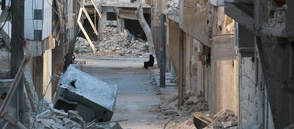 A woman sits amid damaged buildings in the rebel-held al-Myassar neighbourhood of Aleppo - Sputnik Mundo