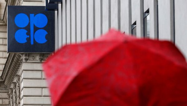 A person carrying an umbrella walks by the OPEC headquarters in Vienna - Sputnik Mundo