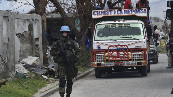 UN soldiers provide security for trucks from the UN's World Foof Programme in Port Salut southwest of Port-au-Prince, on October 12, 2016, following the passage of Hurricane Matthew. The first major handout of food aid took place along Haiti's storm-wrecked southwest coast but supplies were still far short of what was needed by the thousands of starving people. - Sputnik Mundo