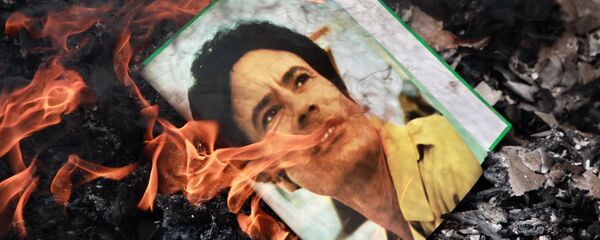 El retrato de Muamar Gadafi, quemado en la calle de Benghazi, Libia, en 2011 - Sputnik Mundo