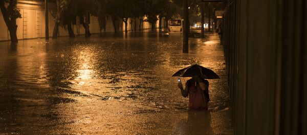 A man wades through a flooded street at the Jardim Botanico neighborhood after heavy rains in Rio de Janeiro, Brazil, Saturday, March 12, 2016 - Sputnik Mundo