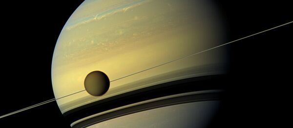 Saturn's largest moon Titan passing in front of the giant planet in an image made by NASA's Cassini spacecraft - Sputnik Mundo