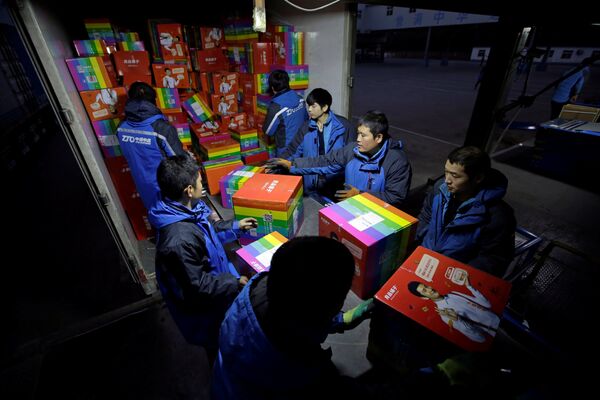 Empleados ordenan paquetes en un centro logístico durante el festival global de compras - Sputnik Mundo