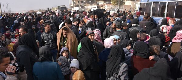Syrians that evacuated the eastern districts of Aleppo gather to board buses, in a government held area in Aleppo, Syria in this handout picture provided by SANA on November - Sputnik Mundo