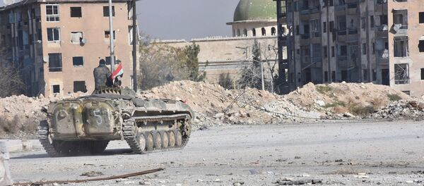 A Syrian government soldier rides a military vehicle near a mosque, after taking control of Aleppo's Al-Haidariya neighbourhood, Syria in this handout picture provided by SANA - Sputnik Mundo