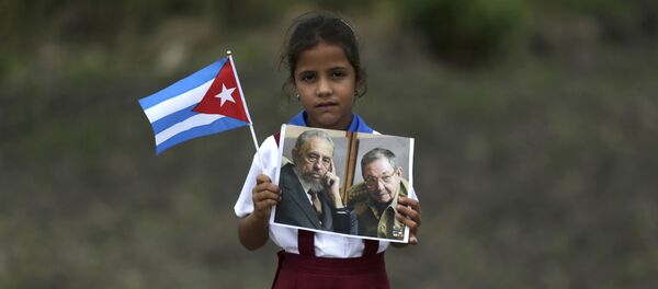 Una niña con las fotos de Fidel y Raúl Castro Una niña con las fotos de Fidel y Raúl Castro - Sputnik Mundo