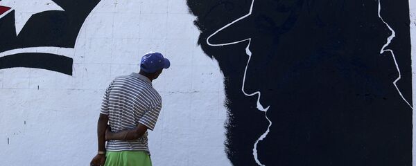 A man looks at a mural representing Cuba's late President Fidel Castro in the outskirts of Santiago de Cuba - Sputnik Mundo