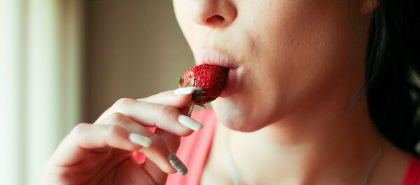 Una mujer comiendo una fresa Una mujer comiendo una fresa - Sputnik Mundo