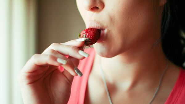 Una mujer comiendo una fresa - Sputnik Mundo