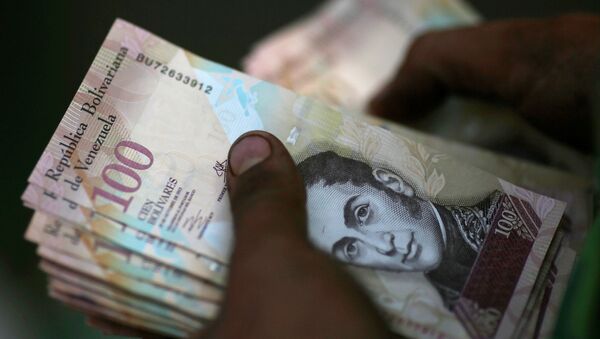 A cashier counts Venezuelan bolivar notes at a street market in downtown Caracas - Sputnik Mundo