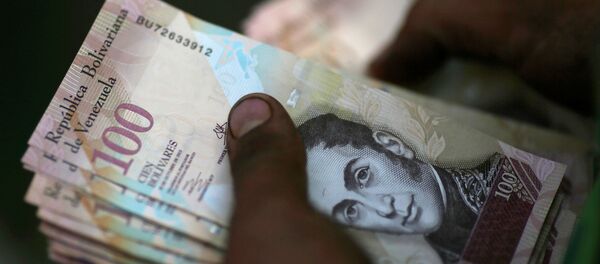 A cashier counts Venezuelan bolivar notes at a street market in downtown Caracas - Sputnik Mundo