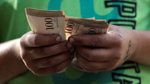 A cashier counts Venezuelan bolivar notes at a street market in downtown Caracas, Venezuela - Sputnik Mundo