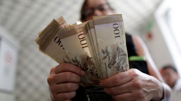 A cashier counts Venezuelan bolivar notes inside a restaurant in downtown Caracas, Venezuela - Sputnik Mundo