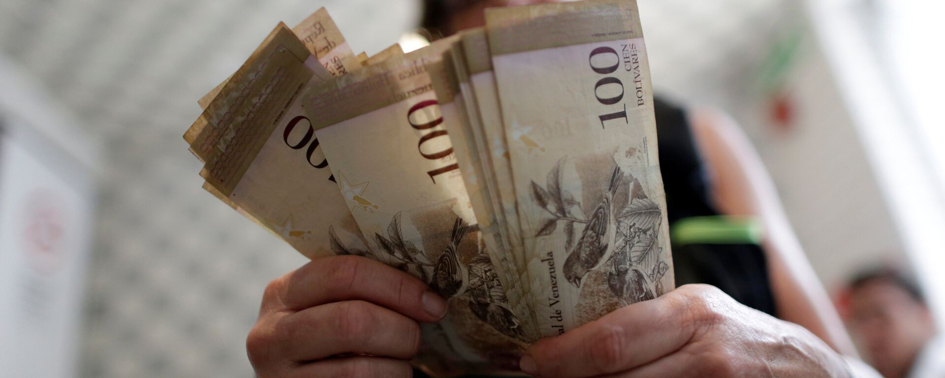 A cashier counts Venezuelan bolivar notes inside a restaurant in downtown Caracas, Venezuela - Sputnik Mundo, 1920, 16.11.2021