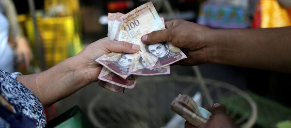 A cashier receives Venezuelan bolivar notes from a customer at a street market in downtown Caracas, Venezuela - Sputnik Mundo