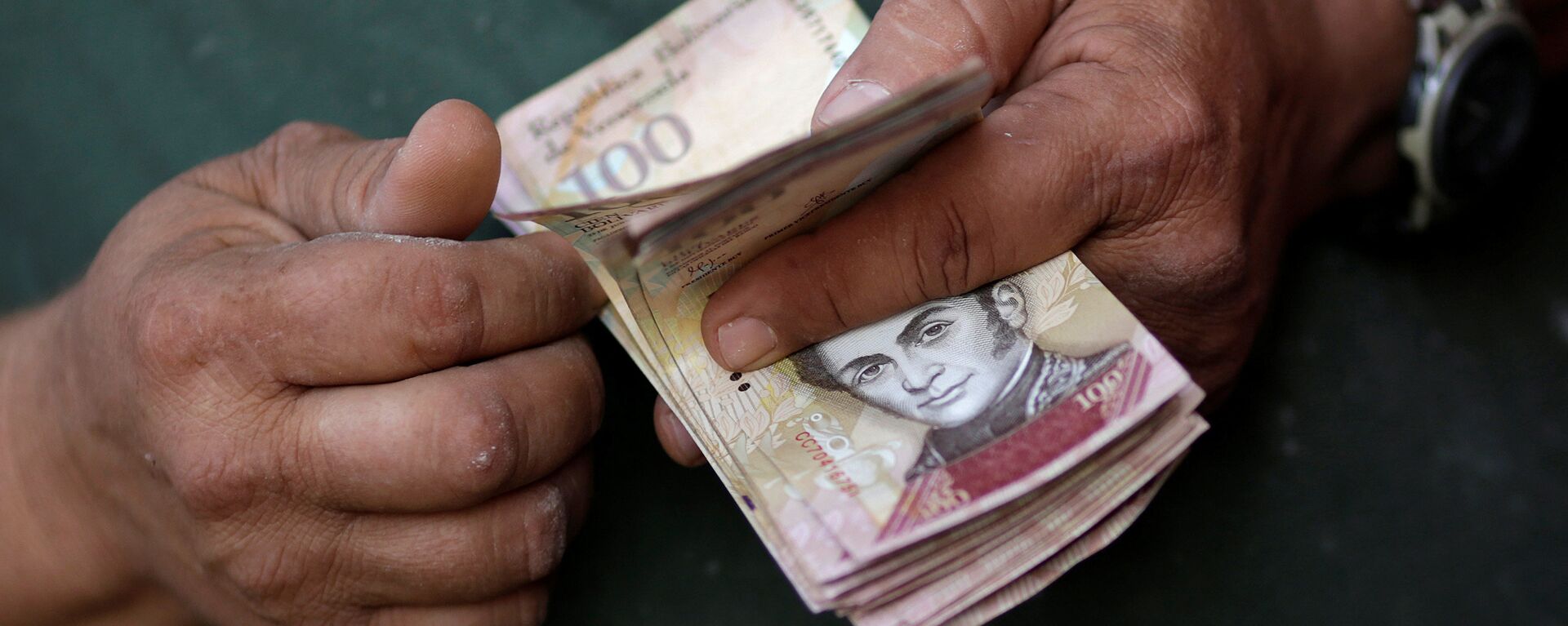 A cashier counts Venezuelan bolivar notes at a street market in downtown Caracas - Sputnik Mundo, 1920, 22.09.2021