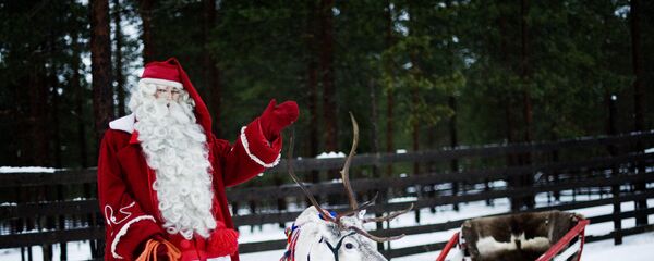 Santa Claus waves as he stands with a reindeer and sled outside Rovaniemi, Finnish Lapland on December 15, 2011 - Sputnik Mundo