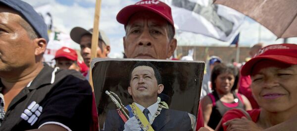 Un chavista en Venezuela con una fotografía de Hugo Chávez - Sputnik Mundo