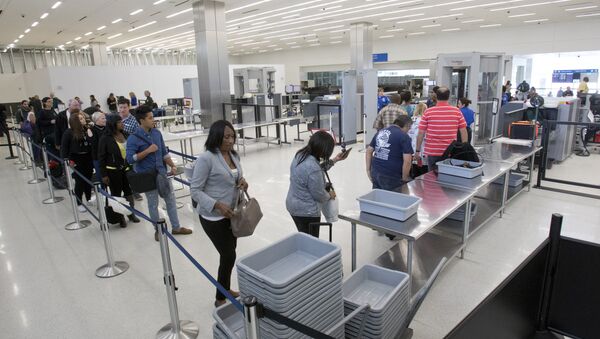 Passengers load their items into bins as they pass through security before flying out of the Fort Lauderdale-Hollywood International Airport, Friday, Dec. 18, 2015 - Sputnik Mundo