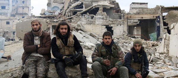 Rebel fighters sit on the rubble of damaged buildings as they wait to be evacuated from a rebel-held sector of eastern Aleppo - Sputnik Mundo
