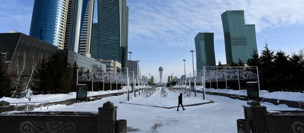 A picture taken on January 22, 2017 shows a man walking in downtown Astana, with the Baiterek monument seen in the background - Sputnik Mundo