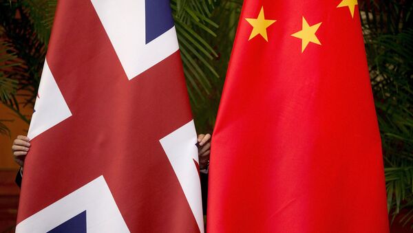 A worker adjusts British and China (R) national flags - Sputnik Mundo