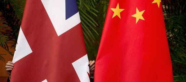 A worker adjusts British and China (R) national flags - Sputnik Mundo