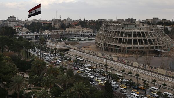 A Syrian national flag waves as vehicles move slowly in a traffic jam during rush hours on a road in Damascus , Syria (File) - Sputnik Mundo