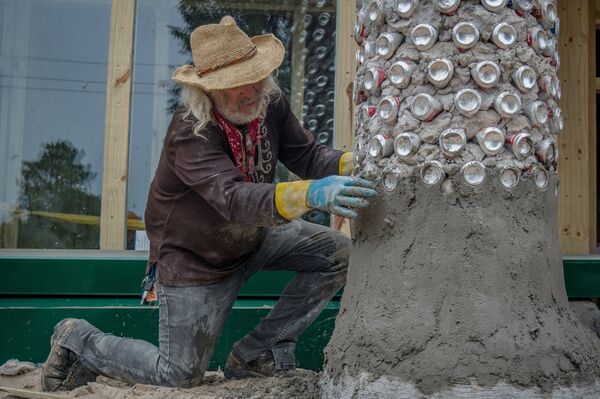 Hombre construyendo columna de latas y barro Hombre construyendo columna de latas y barro - Sputnik Mundo