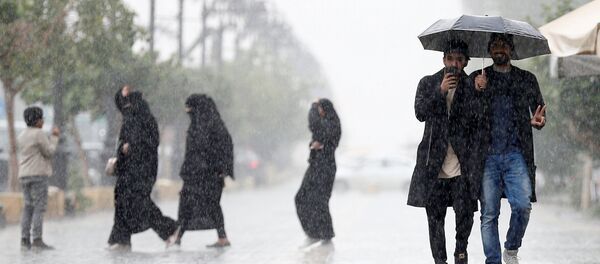 La gente bajo la lluvia en una calle de Riad - Sputnik Mundo