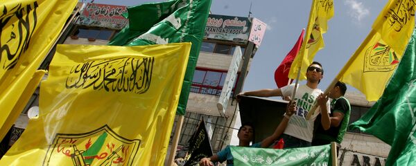 Palestinian supporters of Hamas Islamist movement and of Fatah party wave their faction's flags during a rally to support the Palestinian political unity deal, in the West Bank city of Jenin. (File) - Sputnik Mundo
