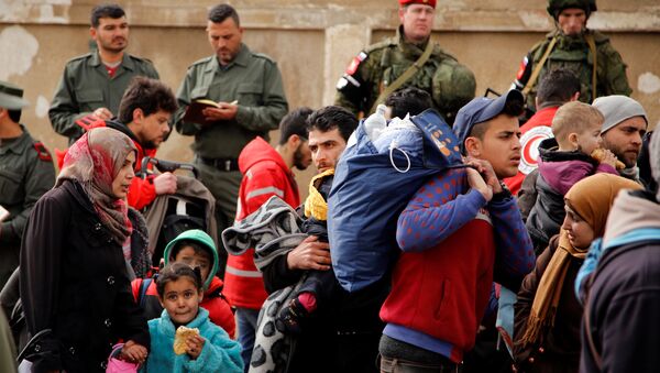 Syrian army soldiers (back L) and Russian soldiers (back R) monitor as rebel fighters and their families evacuate the besieged Waer district in the central Syrian city of Homs - Sputnik Mundo