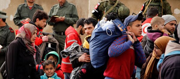 Syrian army soldiers (back L) and Russian soldiers (back R) monitor as rebel fighters and their families evacuate the besieged Waer district in the central Syrian city of Homs - Sputnik Mundo