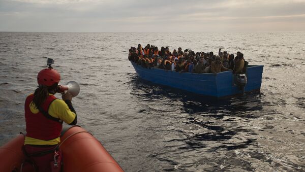 Migrants and refugees are assisted by members of the Spanish NGO Proactiva Open Arms, as they crowd aboard a boat sailing out of control in the Mediterranean Sea about 21 miles north of Sabratha, Libya, on Friday, Feb. 3, 2017. European Union leaders are poised to take a big step on Friday in closing off the illegal migration routes from Libya across the central Mediterranean, where thousands have died trying to reach the EU, the EU foreign affairs chief Federica Mogherini said. - Sputnik Mundo