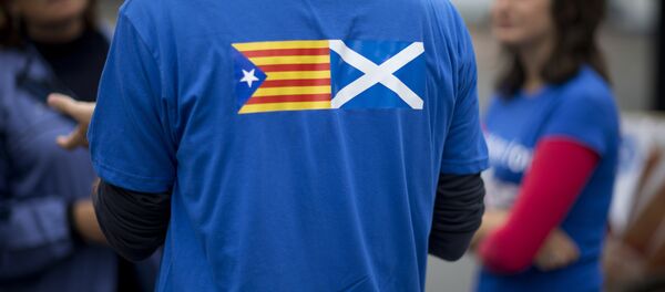 David Aguilar who is visiting Scotland from Catalonia to support the Scottish independence referendum, wears a t-shirt printed with a design showing an estelada Catalan pro-independence flag, left, next to a Scottish Saltire flag as he speaks to passersby in Edinburgh, Scotland, Thursday, Sept. 18, 2014 - Sputnik Mundo
