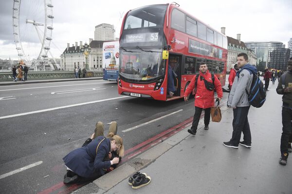 A woman assist an injured person after an incident on Westminster Bridge in London - Sputnik Mundo