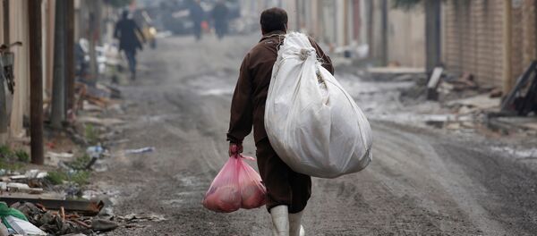 An Iraqi man carries goods from humanitarian aid at Al Ghizlane district as the battle against Islamic State's fighters continues in Mosul, Iraq - Sputnik Mundo