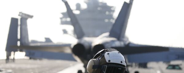 Un miembro de la tripulación de la Marina estadounidense al lado del caza F / A-18 Super Hornet que se prepara para despegar del USS Ronald Reagan, portaaviones de la clase Nimitz de propulsión nuclear - Sputnik Mundo