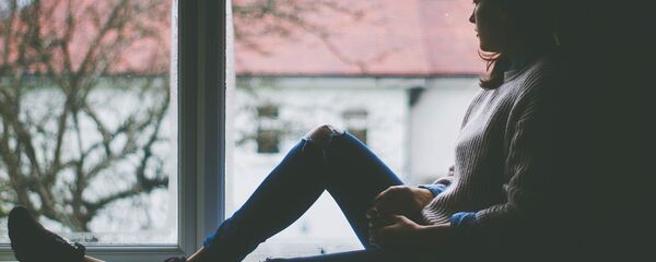 Una mujer pensativa mira por la ventana (imagen referencial) - Sputnik Mundo