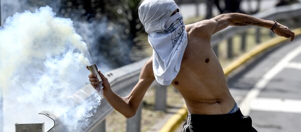 Un hombre lanza gas lacrimógeno, Caracas, Venezuela (archivo) - Sputnik Mundo