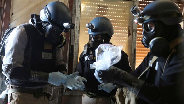 A U.N. chemical weapons expert, wearing a gas mask, holds a plastic bag containing samples from one of the sites of an alleged chemical weapons attack in the Ain Tarma neighbourhood of Damascus, Syria. (File) - Sputnik Mundo