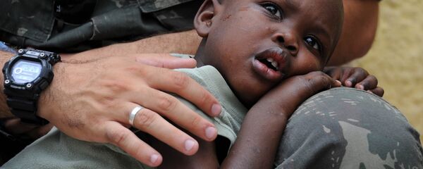 Un niño de Haití, en el regazo de un Casco Azul - Sputnik Mundo