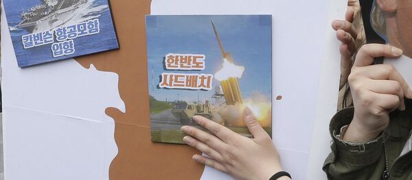 Los manifestantes llevan un recorte del presidente estadounidense Donald Trump y las imágenes del portaviones USS Carl Vinson y del sistema de defensa antimisiles estadounidense THAAD en un mapa de la Península Coreana - Sputnik Mundo