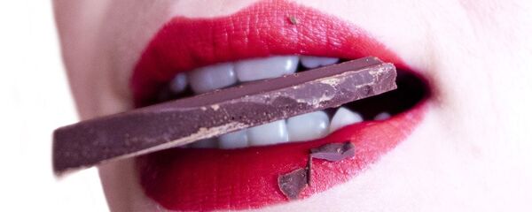 Una mujer comiendo chocolate - Sputnik Mundo