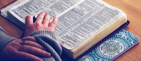 Una persona lee una biblia - Sputnik Mundo